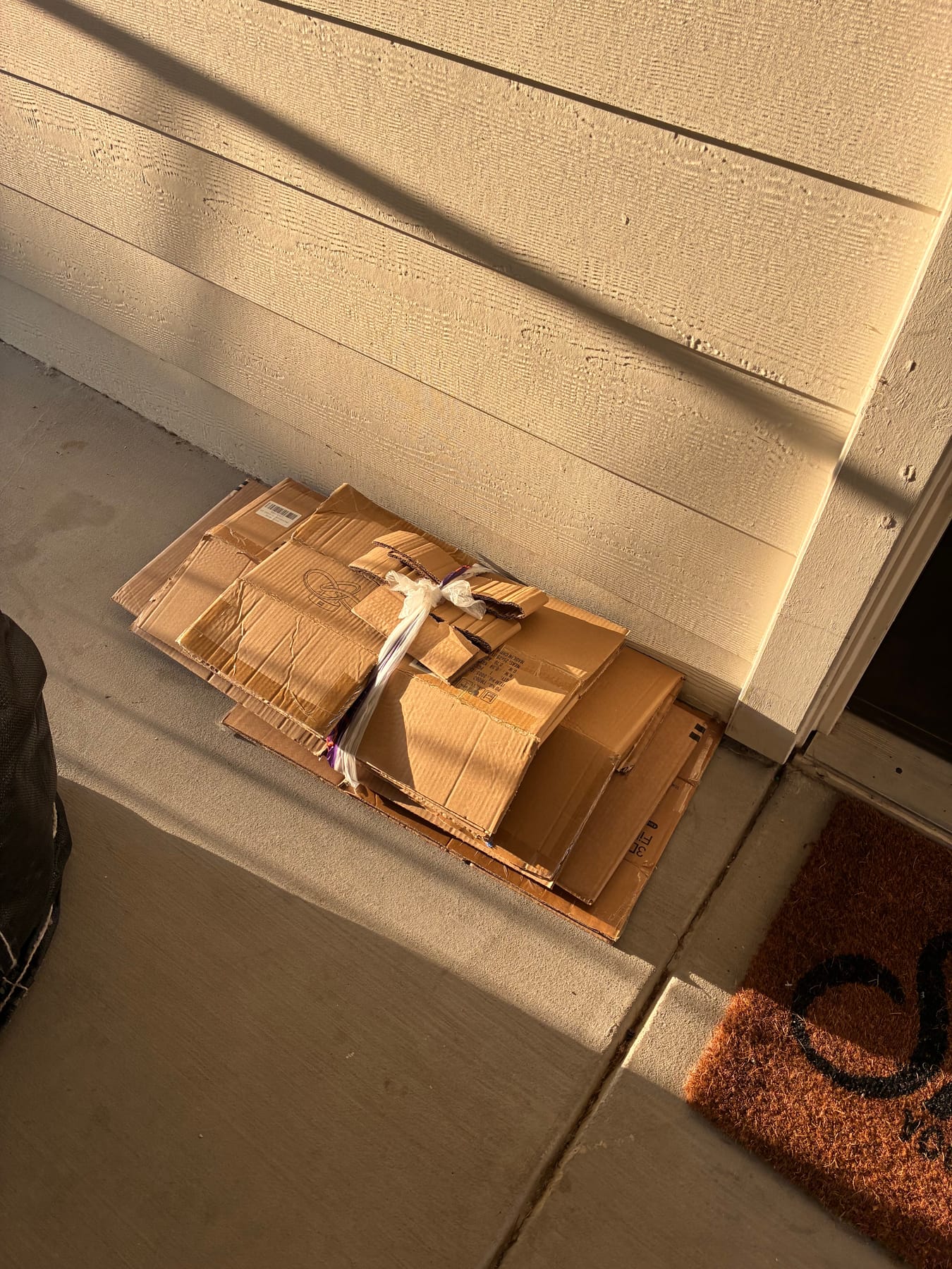 Flattened cardboard bundled and tied at a doorstep for pickup
